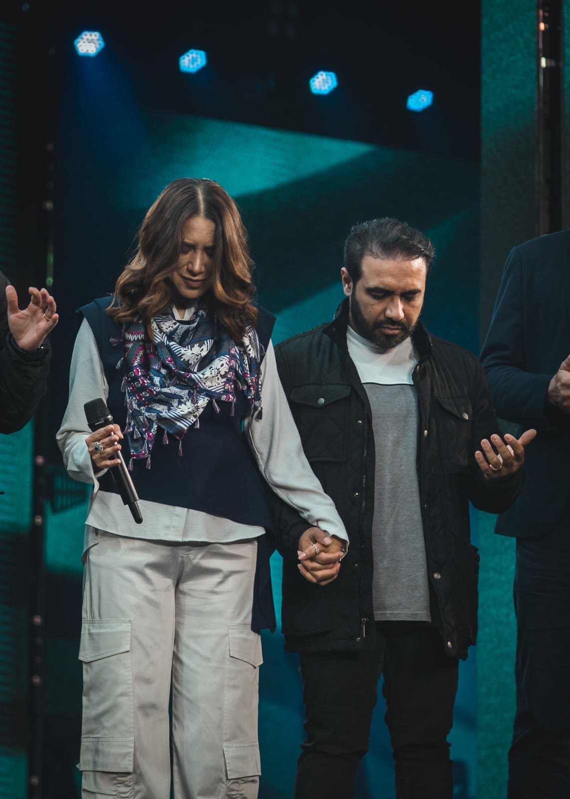 Casal de mãos dadas em oração no palco
